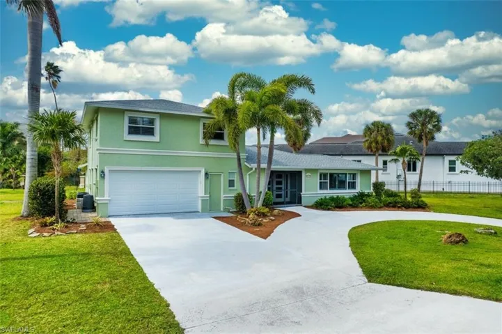 View of front of property with fence, a front lawn, concrete driveway, and stucco siding