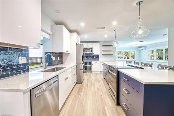 Kitchen with a spacious island, visible vents, appliances with stainless steel finishes, a sink, and light wood-type flooring