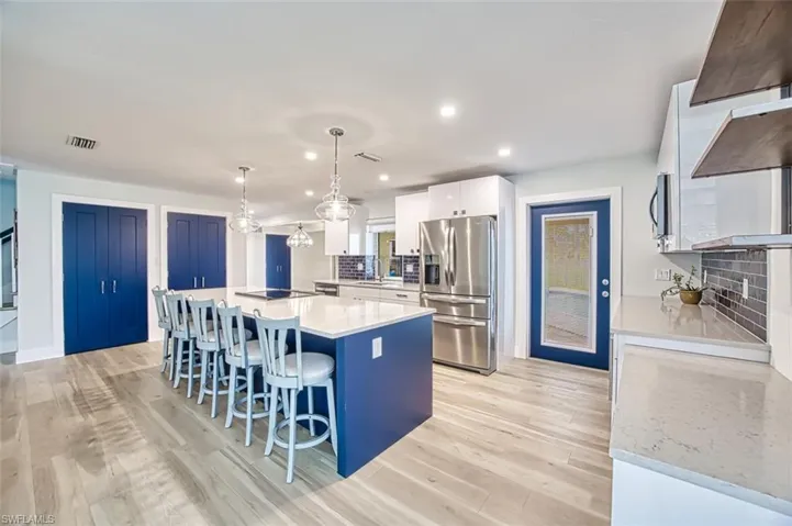 Kitchen with stainless steel appliances, light wood-style flooring, a breakfast bar area, and white cabinetry