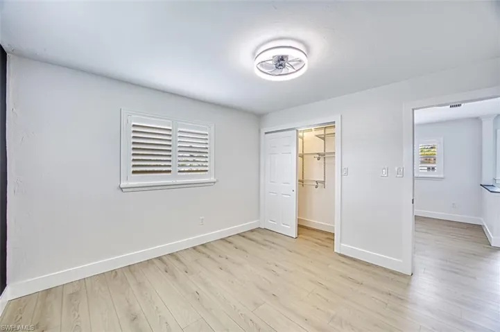 Unfurnished bedroom featuring a closet, light wood-style flooring, and baseboards