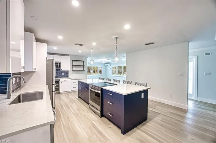 Kitchen featuring stainless steel appliances, visible vents, decorative backsplash, white cabinetry, and a sink