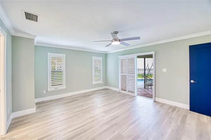 Empty room with baseboards, light wood finished floors, visible vents, and crown molding