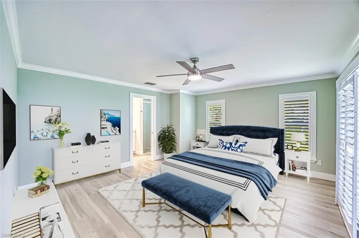 Bedroom with baseboards, visible vents, a ceiling fan, ornamental molding, and wood finished floors