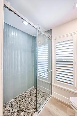 Bathroom featuring toilet, a stall shower, and wood finished floors