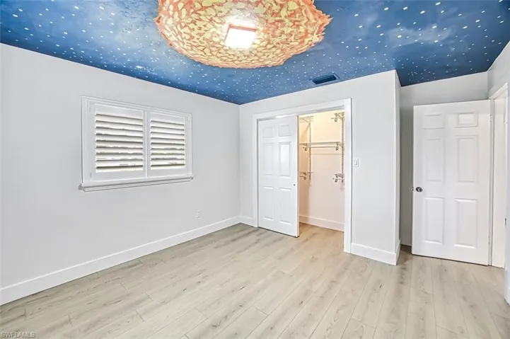 Unfurnished bedroom with wood finished floors, visible vents, and baseboards