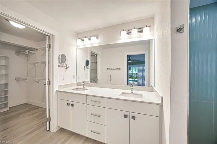 Bathroom with double vanity, a sink, baseboards, and wood finished floors