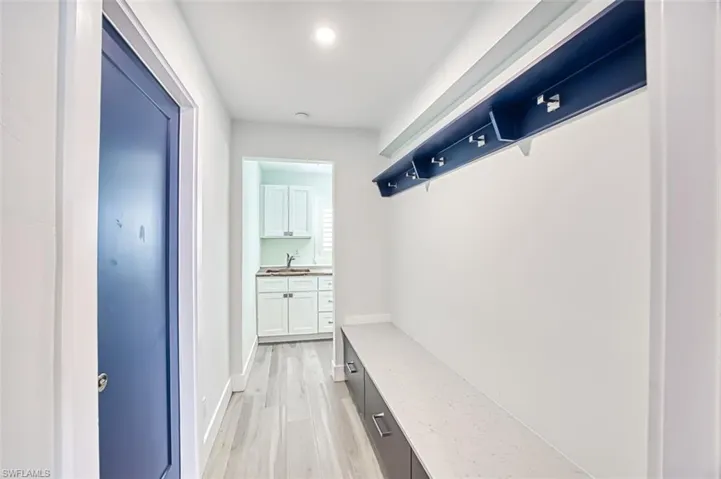 Mudroom featuring light wood-type flooring, a sink, and baseboards