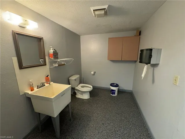 Bathroom with a textured ceiling and toilet