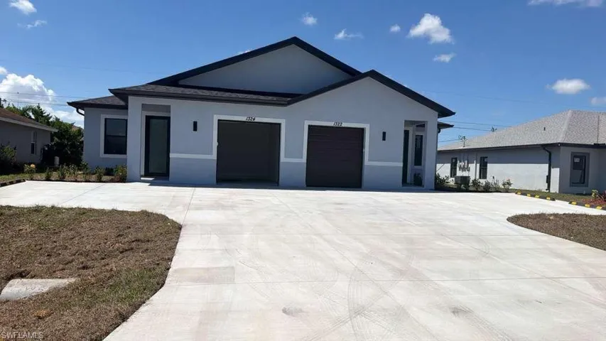 Contemporary duplex featuring a light gray and white stucco exterior, dark asphalt shingle roof, two distinct entryways, and twin garage doors