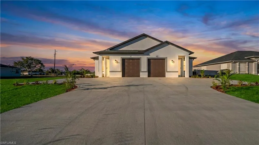 Contemporary stucco exterior with twin dark wood-finish garage doors, accented by modern exterior lighting fixtures