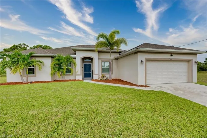 View of front of house with stucco siding, driveway, an attached garage, and a front yard