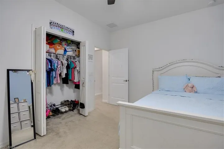 Bedroom with light carpet, ceiling fan, and a closet