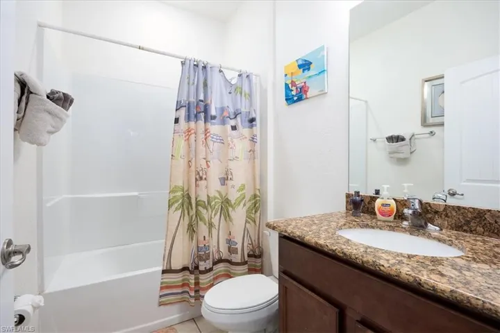 Bathroom featuring shower / bath combo with shower curtain, vanity, and light tile patterned floors