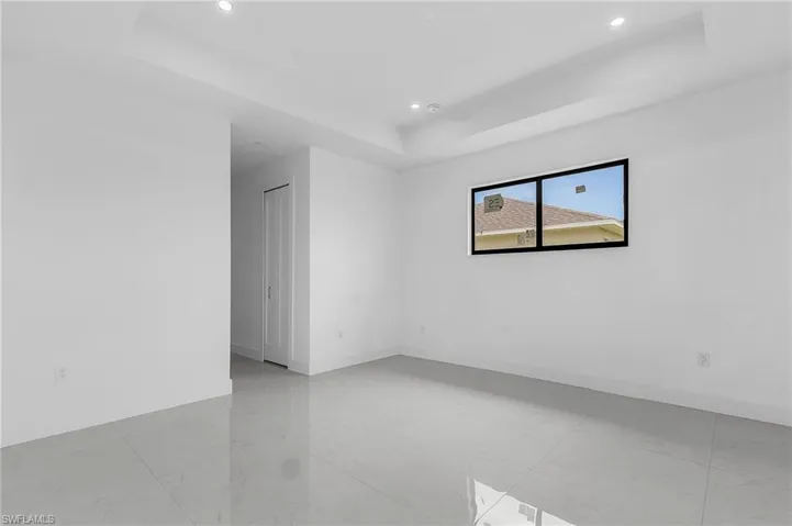 Tiled empty room featuring a tray ceiling