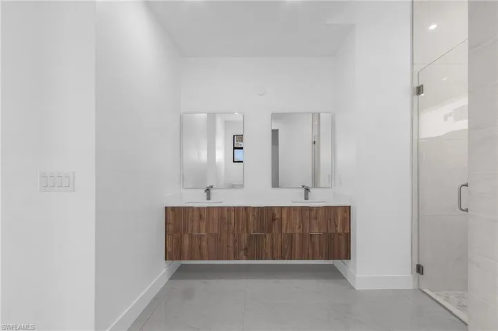 Bathroom with tile patterned floors, a shower with door, and double sink vanity