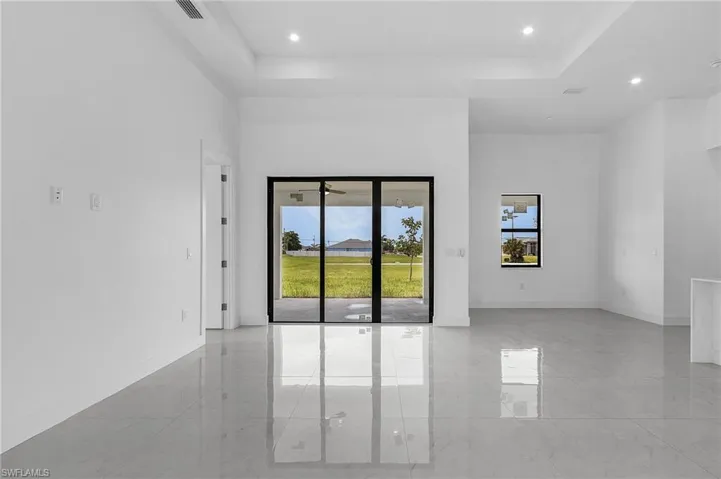 Tiled empty room with a raised ceiling and a healthy amount of sunlight