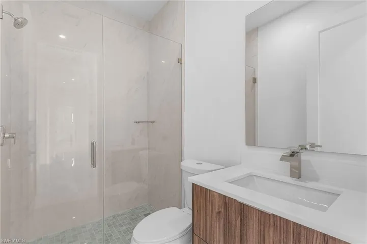 Bathroom with a shower with door, toilet, and vanity