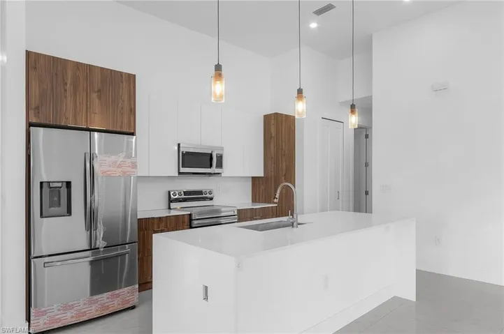 Kitchen featuring white cabinetry, stainless steel appliances, pendant lighting, sink, and light tile patterned floors