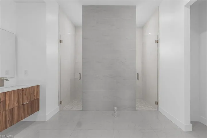 Bathroom featuring vanity, walk in shower, and tile patterned flooring