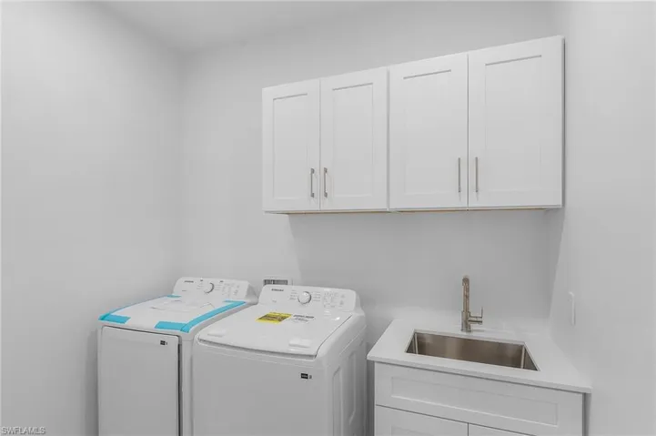 Laundry room with sink, cabinets, and washing machine and clothes dryer