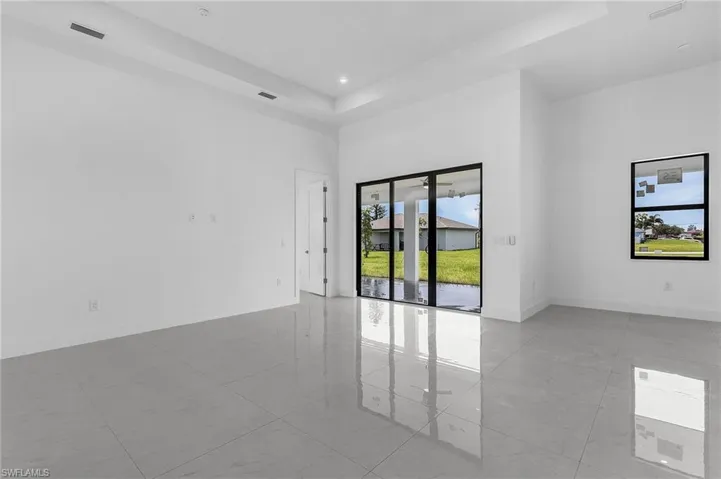 Tiled empty room with a raised ceiling and a high ceiling