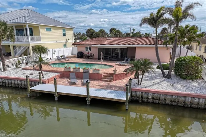 Rear view of property featuring a tile roof, a patio area, a fenced in pool, a fenced backyard, and a water view