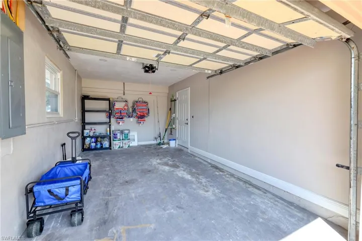 Garage with baseboards, electric panel, and a garage door opener