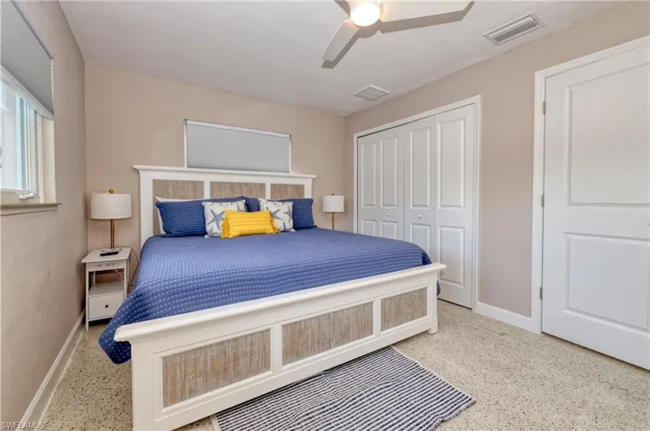 Bedroom with a closet, visible vents, baseboards, speckled floor, and a ceiling fan