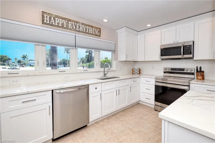 Kitchen featuring white cabinetry, a sink, stainless steel appliances, and tasteful backsplash