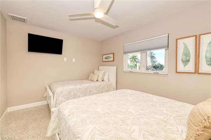 Bedroom with a ceiling fan, speckled floor, baseboards, and visible vents