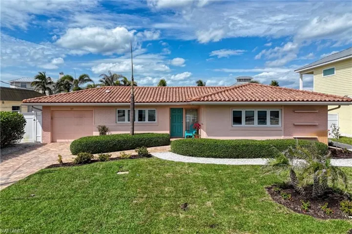 Ranch-style home with decorative driveway, an attached garage, a front yard, a tile roof, and brick siding