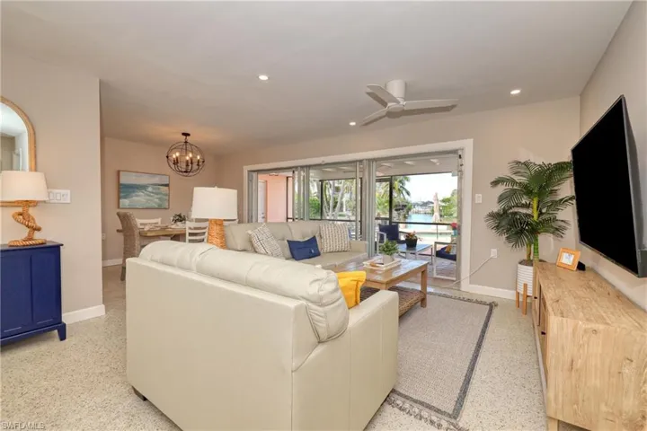 Living area featuring baseboards, recessed lighting, light speckled floor, and ceiling fan with notable chandelier