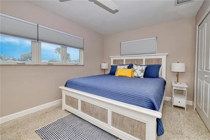 Bedroom with a closet, visible vents, baseboards, ceiling fan, and speckled floor