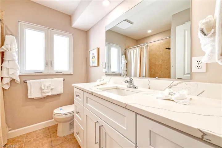 Full bathroom with tile patterned flooring, vanity, toilet, baseboards, and curtained shower