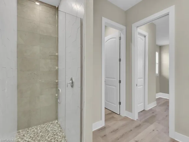 Bathroom featuring a shower with shower door and hardwood / wood-style flooring