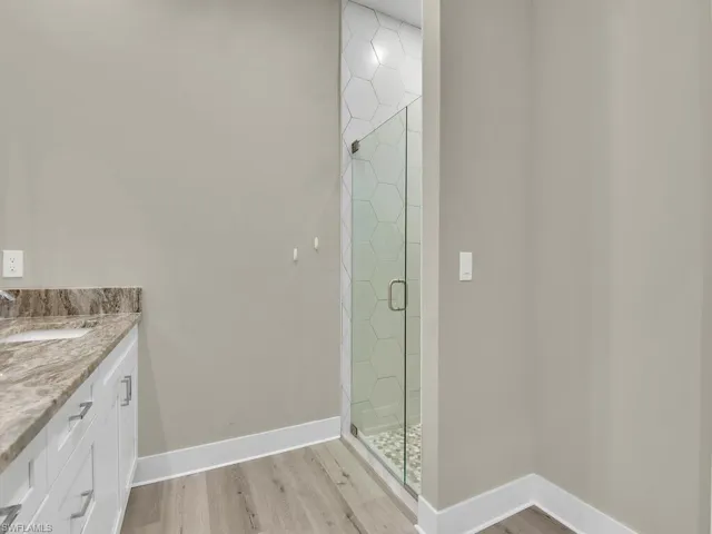 Bathroom with a shower with shower door, wood-type flooring, and vanity