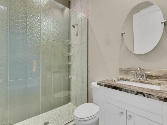 Bathroom featuring a shower with door, oversized vanity, and toilet