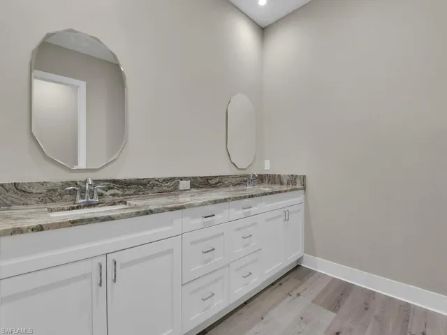 Bathroom with hardwood / wood-style floors, large vanity, and dual sinks