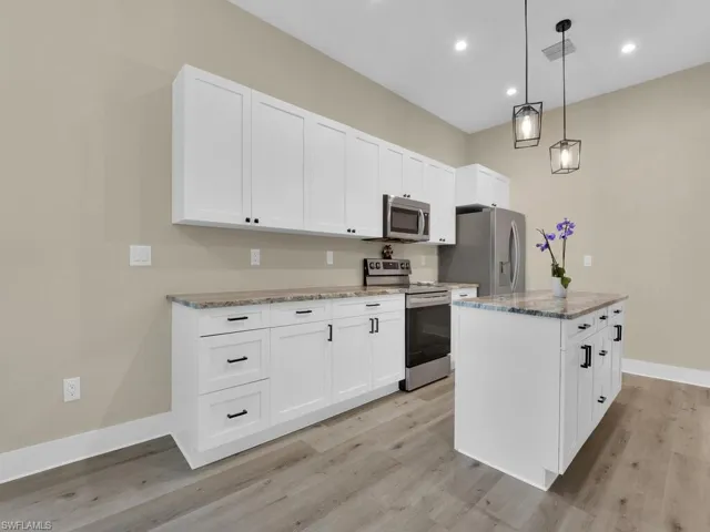 Kitchen featuring stainless steel appliances, light hardwood / wood-style floors, and white cabinets