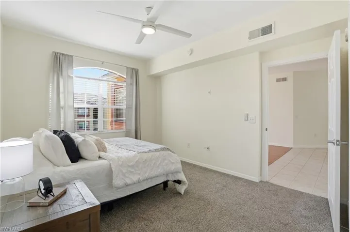 Bedroom featuring light carpet, ceiling fan, and light tile patterned floors