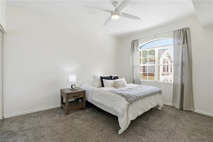 Carpeted bedroom with a ceiling fan and baseboards