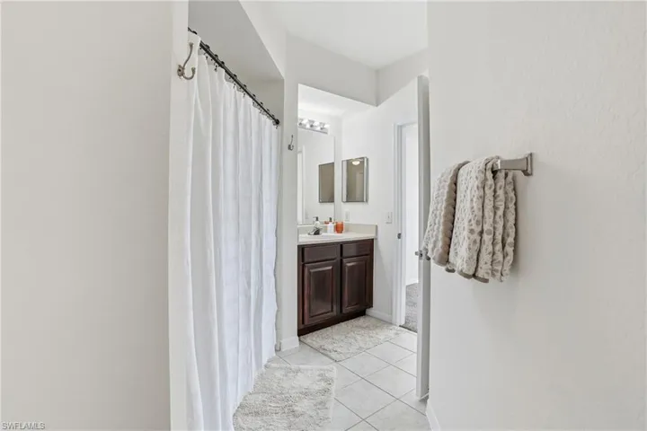 Full bathroom with vanity, curtained shower, and light tile patterned floors