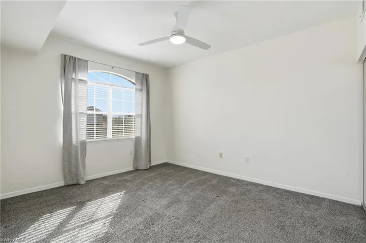 Carpeted spare room featuring baseboards and ceiling fan