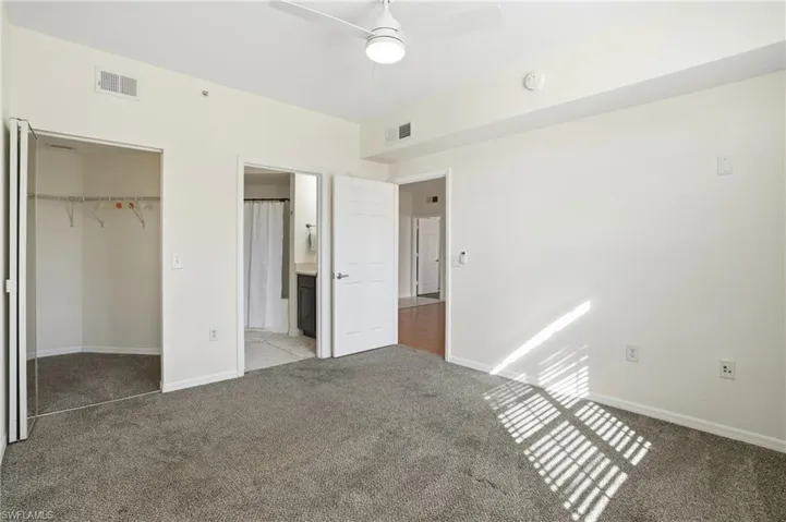 Unfurnished bedroom featuring light colored carpet, ceiling fan, a closet, and ensuite bath