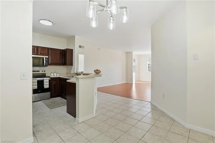 Kitchen with a peninsula, light countertops, stainless steel appliances, light tile patterned flooring, and open floor plan