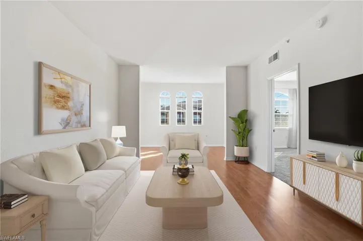 Virtually staged living room featuring healthy amount of natural light and wood finished floors
