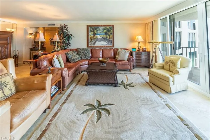 Spacious living area featuring light-toned flooring and a large area rug with palm tree motifs