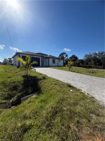 View of front of property featuring decorative driveway, stucco siding, a front lawn, and a garage