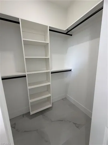 Spacious closet featuring light marble finish floors