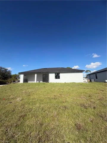 Back of house featuring a yard and stucco siding